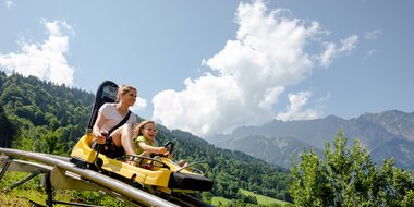 Alpine-Coaster-Golm in Montafon | © Golm Silvretta Lünersee Tourismus GmbH Bregenz, Stefan Kothner A woman and a child ride down the mountain on a summer roller coaster | © Golm Silvretta Lünersee Tourismus GmbH Bregenz, Stefan Kothner