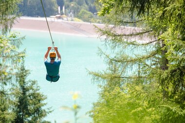 Flying-Fox-Golm in Montafon | © Golm Silvretta Lünersee Tourismus GmbH Bregenz, Stefan Kothner A girl flying over the Latschau reservoir attached to a 565 m long steel cable | © Golm Silvretta Lünersee Tourismus GmbH Bregenz, Stefan Kothner