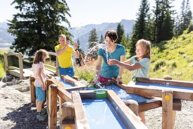Golmis Forschungspfad at Erlebnisberg Golm | © Golm Silvretta Lünersee Tourismus GmbH Bregenz, Stefan Kothner Father and mother discovering the power of water together with their two daughters while playing water games on Golmis Forschungspfad | © Golm Silvretta Lünersee Tourismus GmbH Bregenz, Stefan Kothner