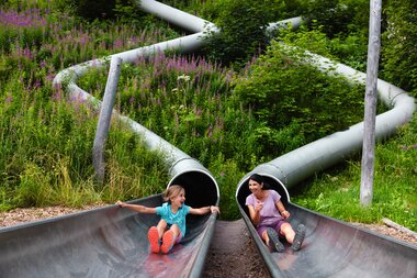 Mom and child sliding down the two different slides in the Waldrutschenpark-Golm | © Golm Silvretta Lünersee Tourismus GmbH Bregenz, Mathäus Gartner Waldrutschenpark-Golm in Montafon | © Golm Silvretta Lünersee Tourismus GmbH Bregenz, Mathäus Gartner
